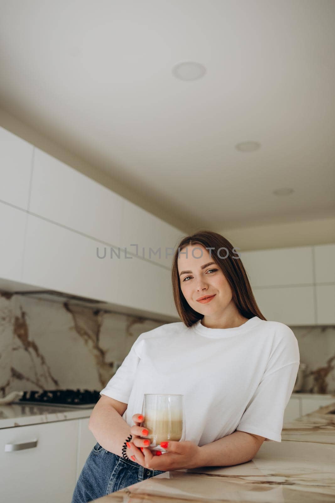 Beautiful young woman drinking coffee in kitchen by fentonroma