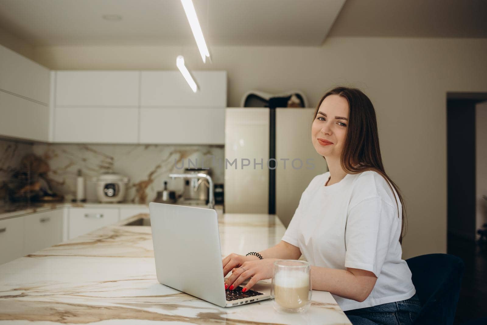 Focused young woman sitting at her kitchen table at home working on her small business with a laptop by fentonroma