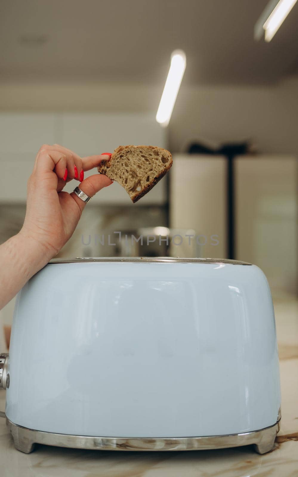 Young woman using toaster at table in kitchen.