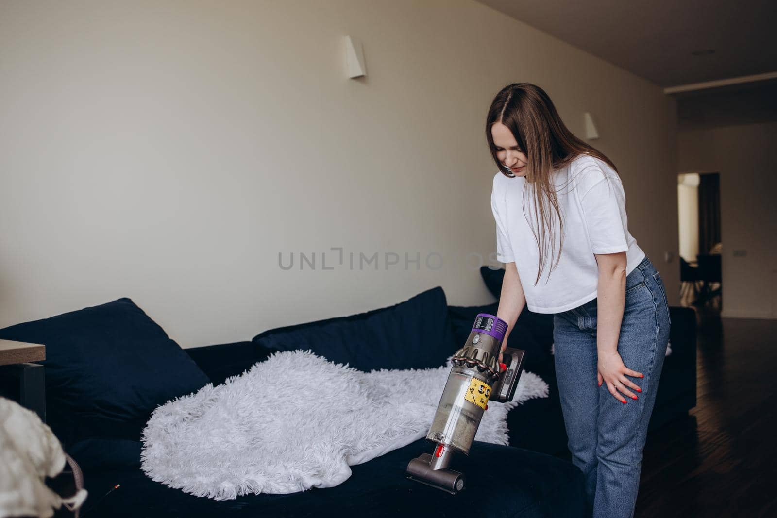 Young woman with rechargeable vacuum cleaner cleaning at home.