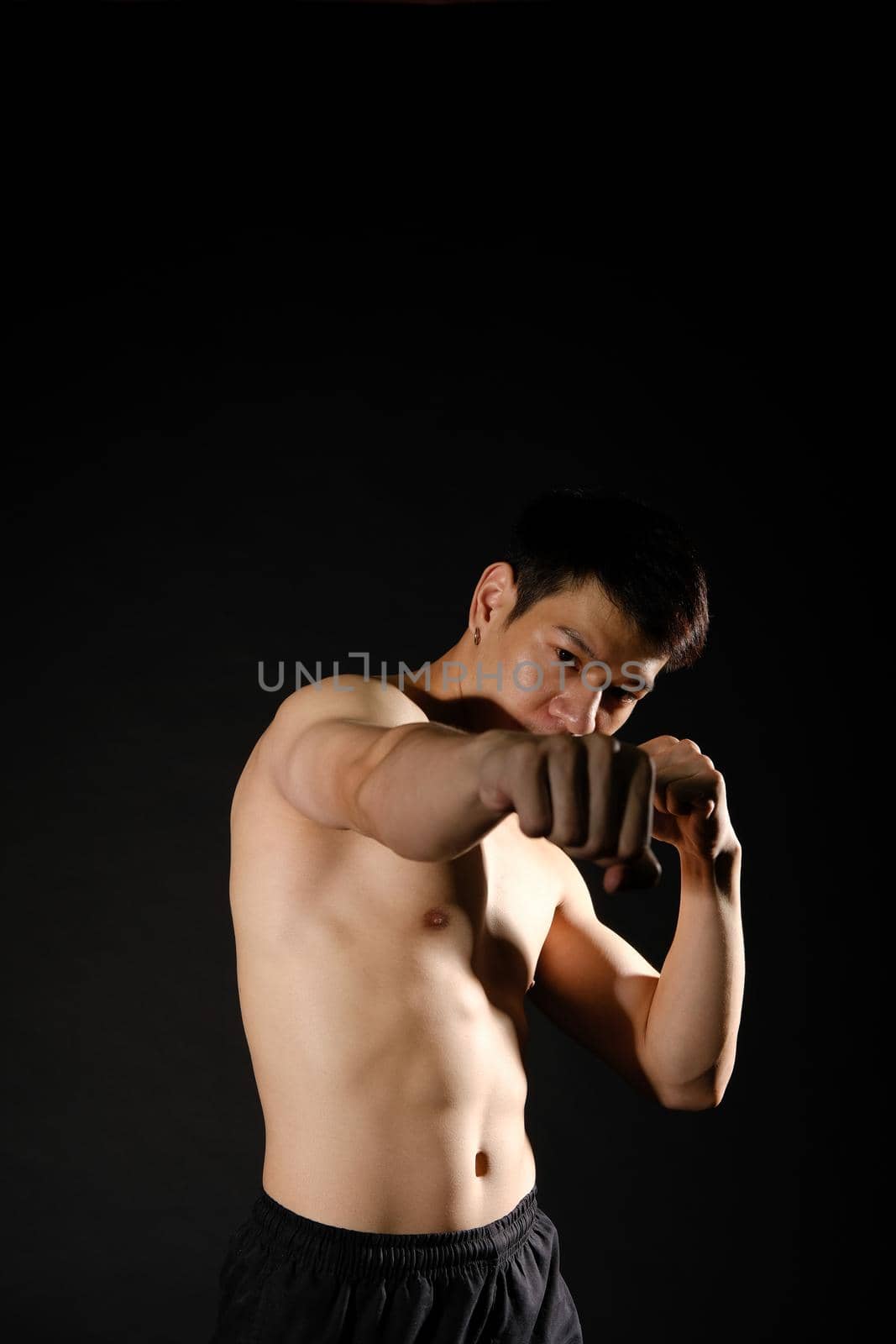 portrait of athletic muscular bodybuilder man with naked torso six pack abs boxing punching. fitness workout concept