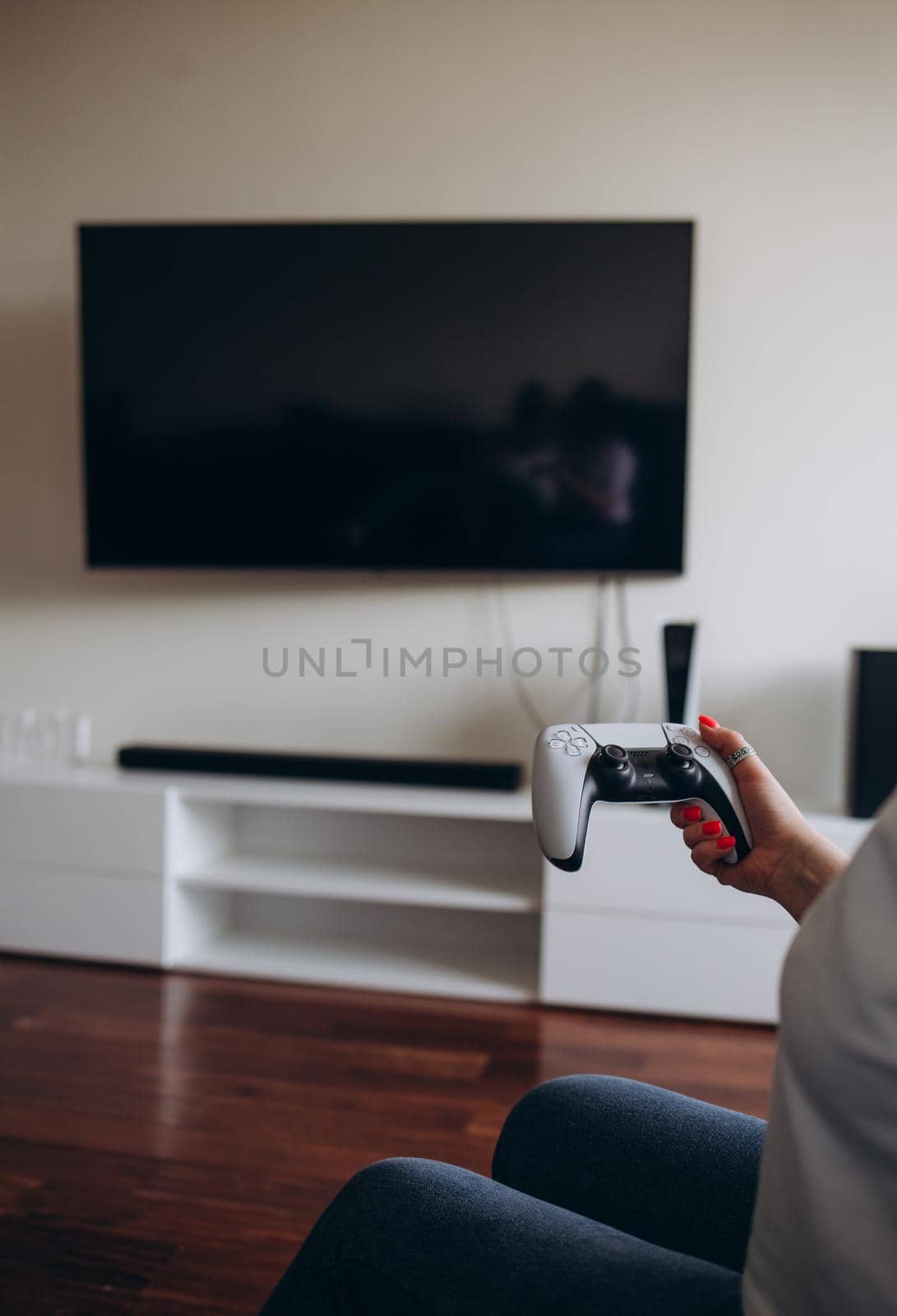 A young woman is playing a game console. Girl gamer and computer video games. The streamer holds a joystick in her hands. Person at home at night