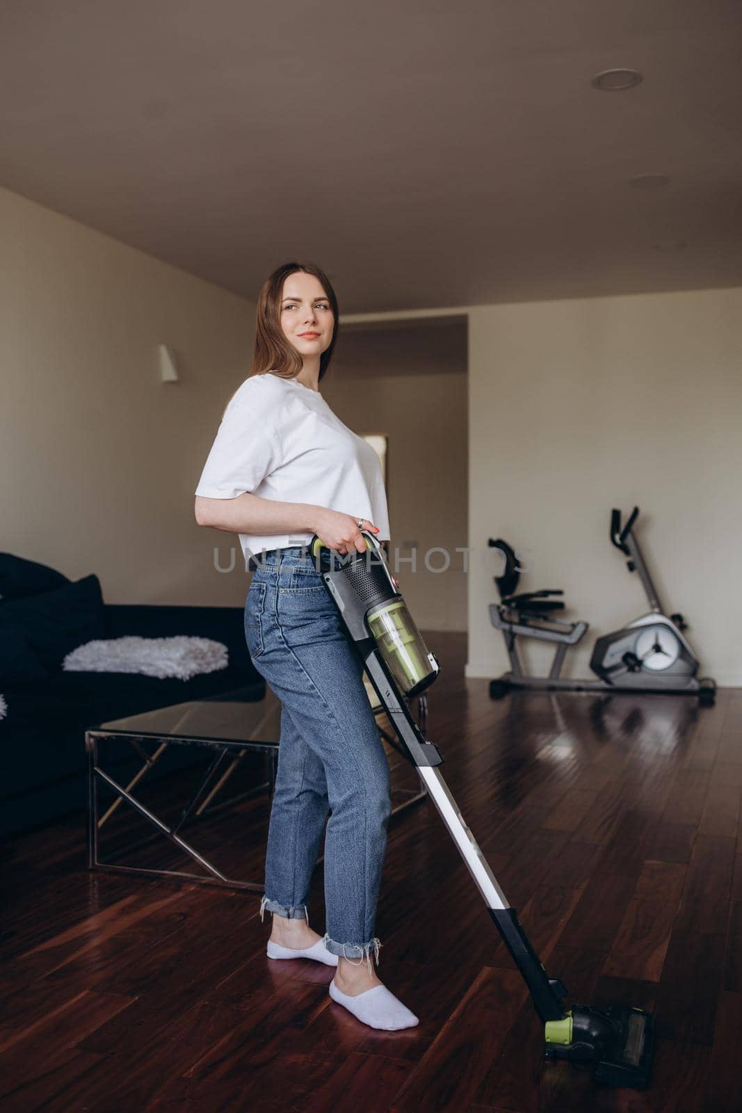 Young Maid Cleaning Carpet With Vacuum Cleaner At Home.