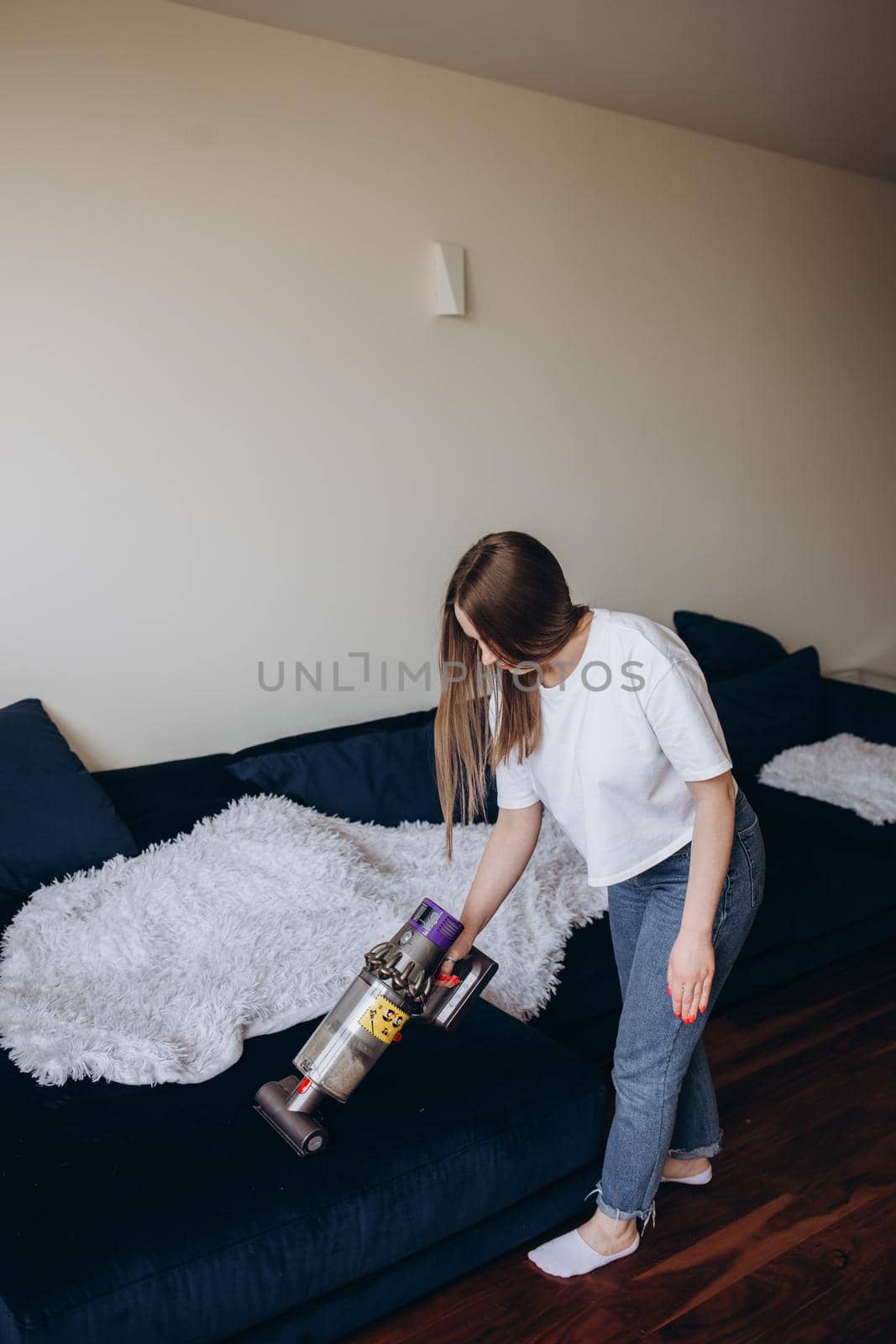 Young woman with rechargeable vacuum cleaner cleaning at home.