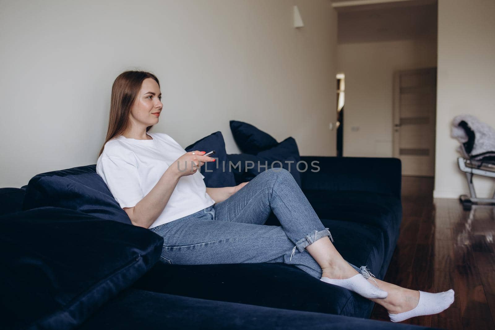 Young woman changing channels with remote control.