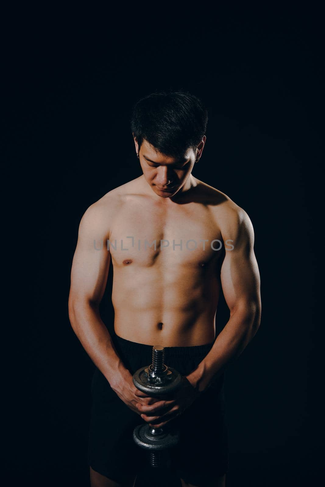 portrait of athletic muscular bodybuilder man with naked torso six pack abs working out with dumbbell. fitness sport exercise concept