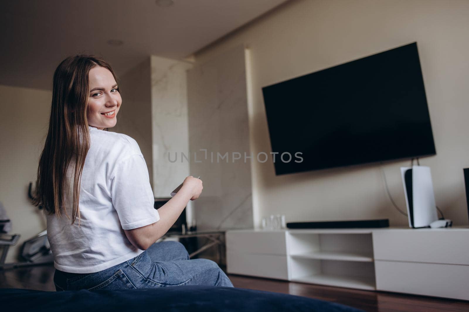 Young Woman Sitting On Couch Watching Movie On Television At Home.