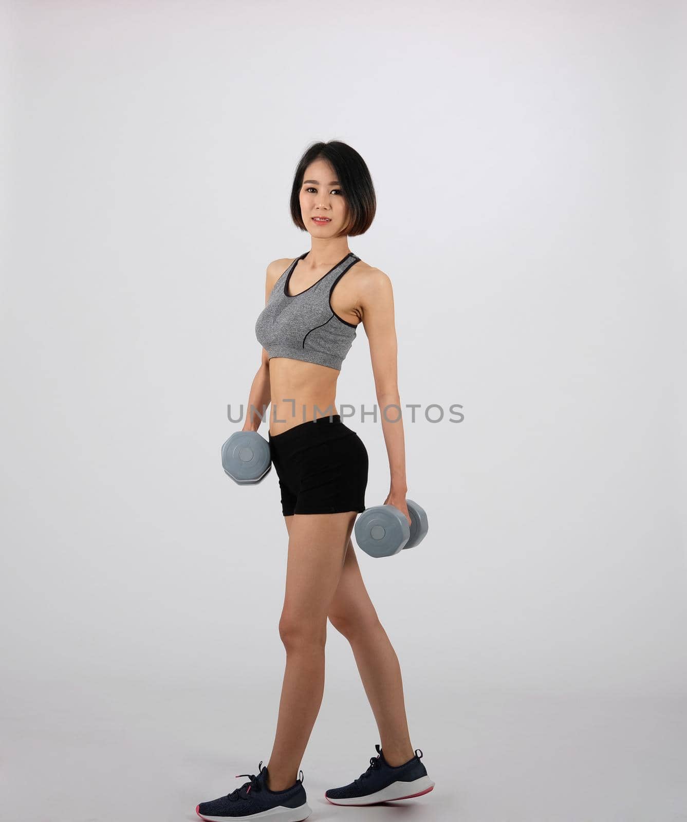 asian sporty woman in sportswear with dumbbell doing fitness workout on white background. healthy sport lifestyle