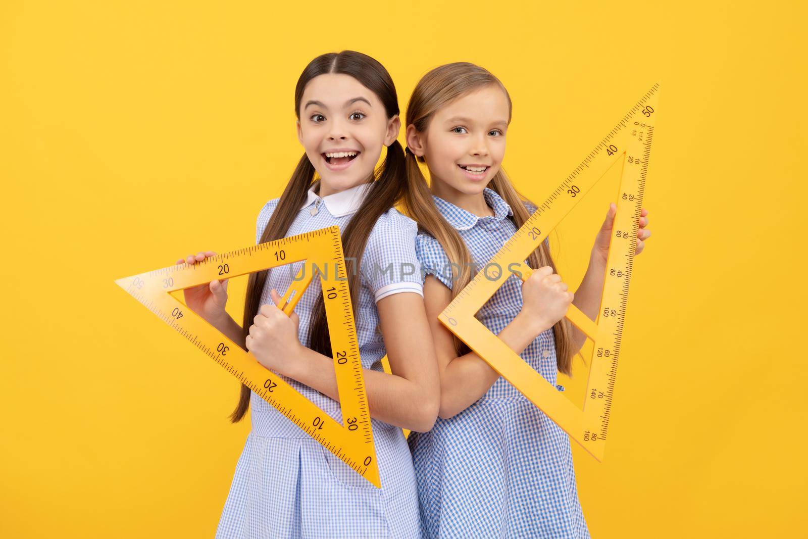 Education for all children. Happy teen girls hold triangular rulers. School education. Geometry lesson by RedFoxStudio