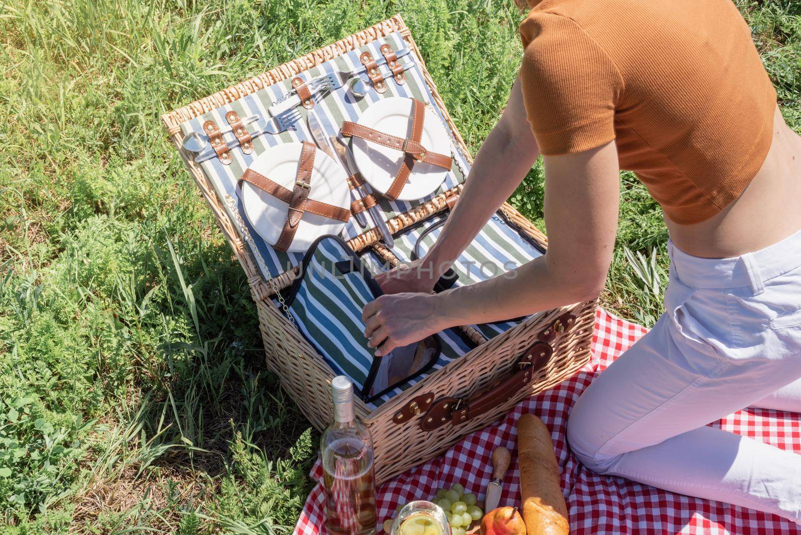 young caucasian woman preparing picnic basket outdoors, ready to have a picnic by Desperada