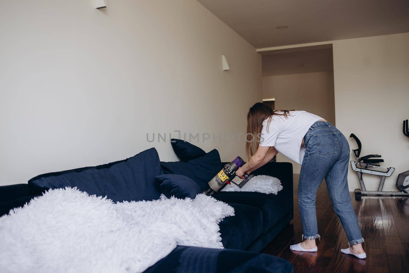 Young woman with rechargeable vacuum cleaner cleaning at home by fentonroma