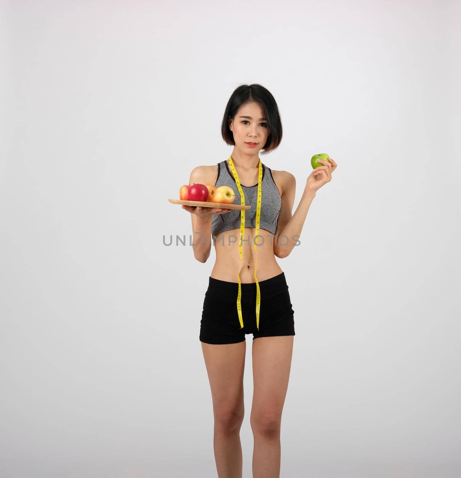 sporty fitness woman in sportswear with apple on white background. healthy sport lifestyle