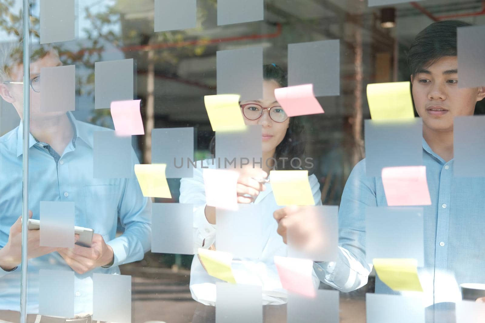business people working planning discussing idea with sticky reminder note on glass wall by pp99