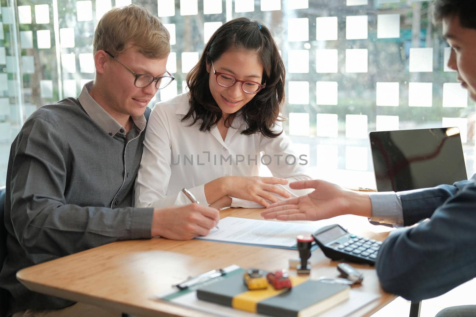 couple buying renting house car signing mortgage insurance purchase order contract agreement with realtor real estate agent. by pp99