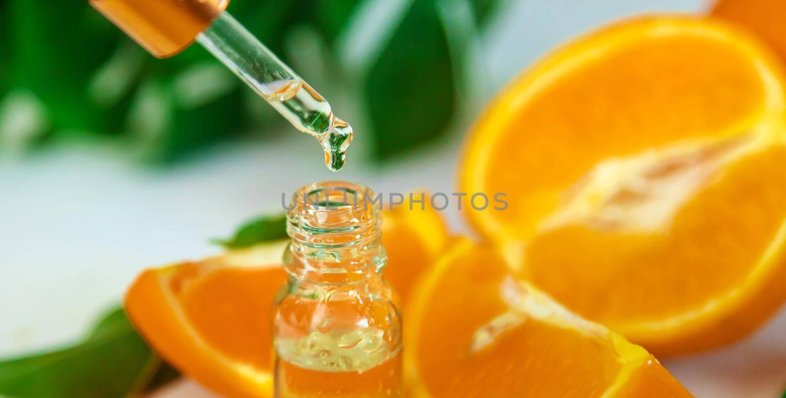 Orange essential oil in a small bottle. Selective focus. Nature.