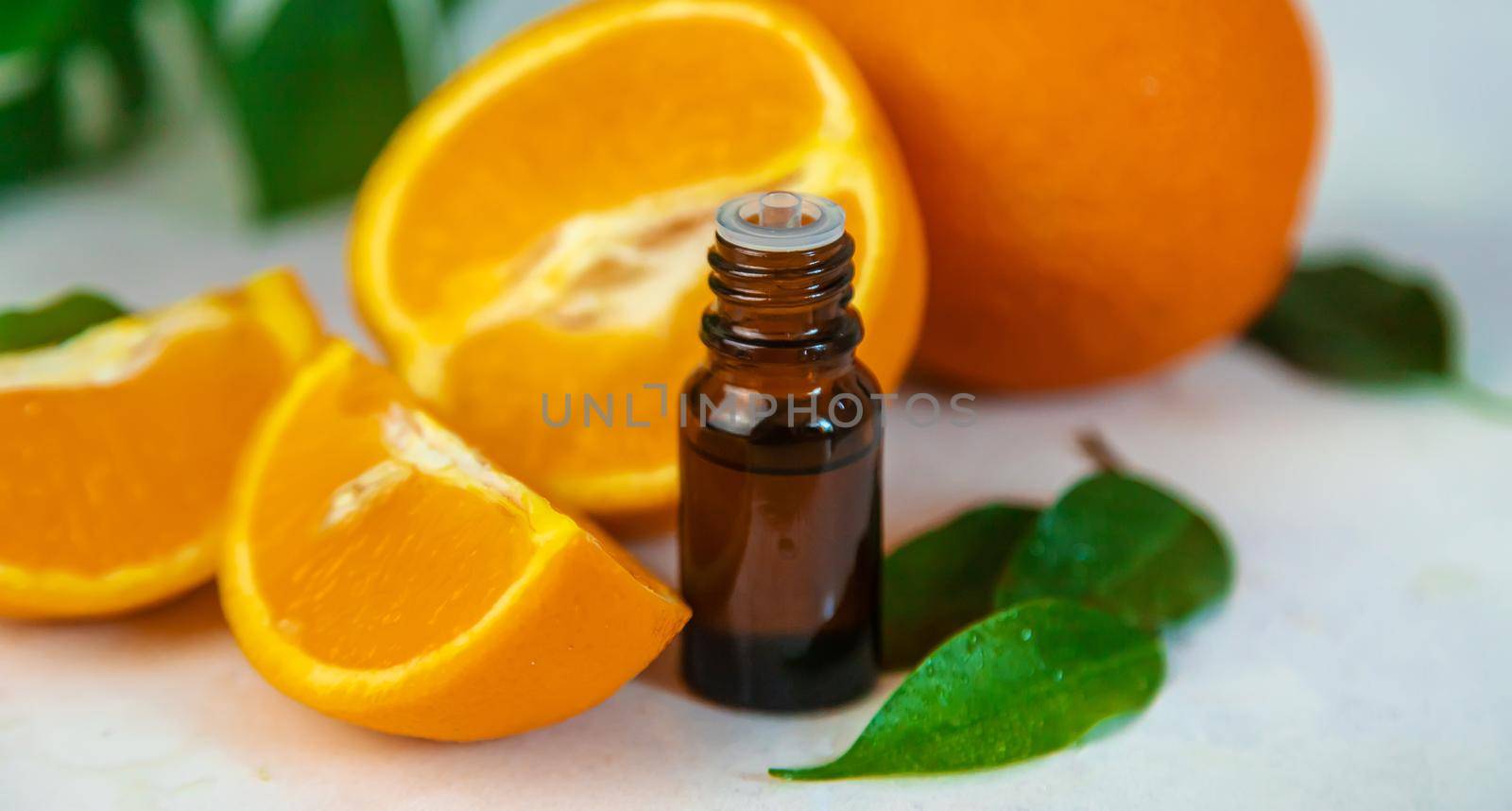 Orange essential oil in a small bottle. Selective focus. by yanadjana