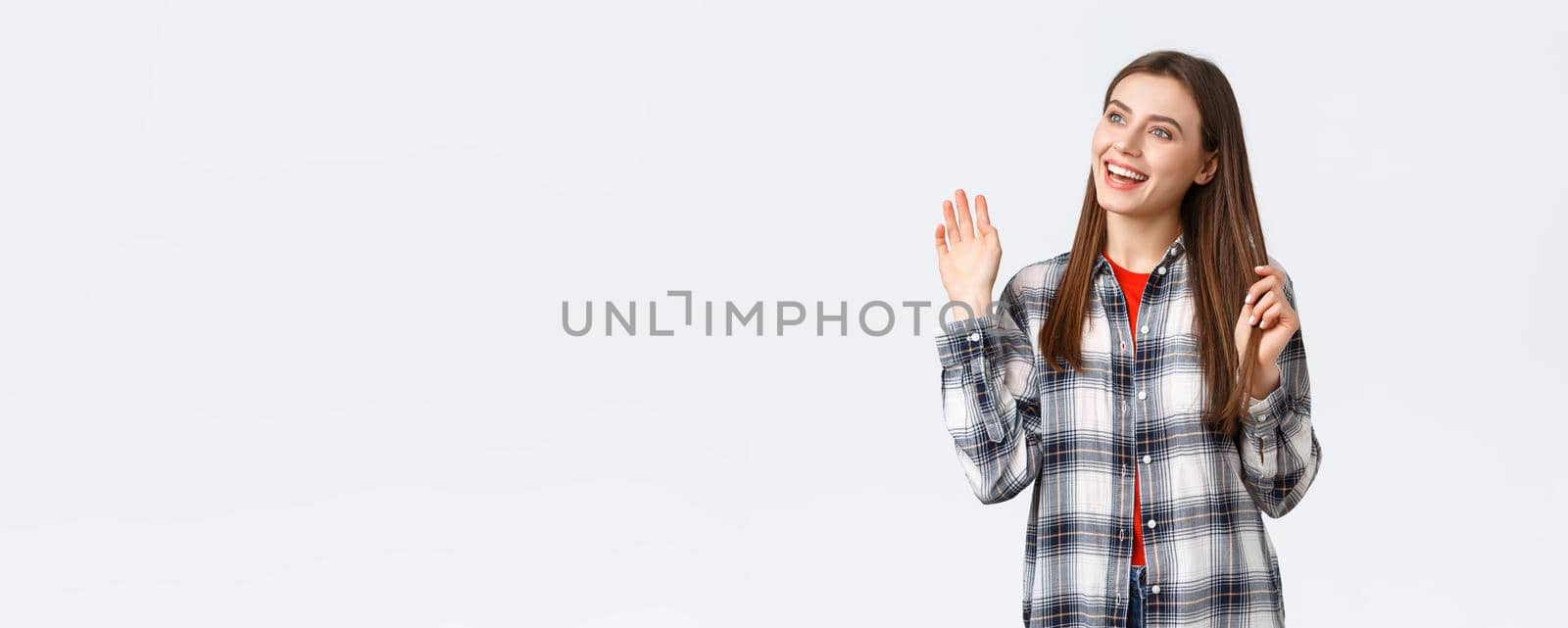 Lifestyle, different emotions, leisure activities concept. Cheerful, friendly attractive woman saying hi, meeting person at cafe, turn head and looking left, waving hello, greeting gesture by Benzoix