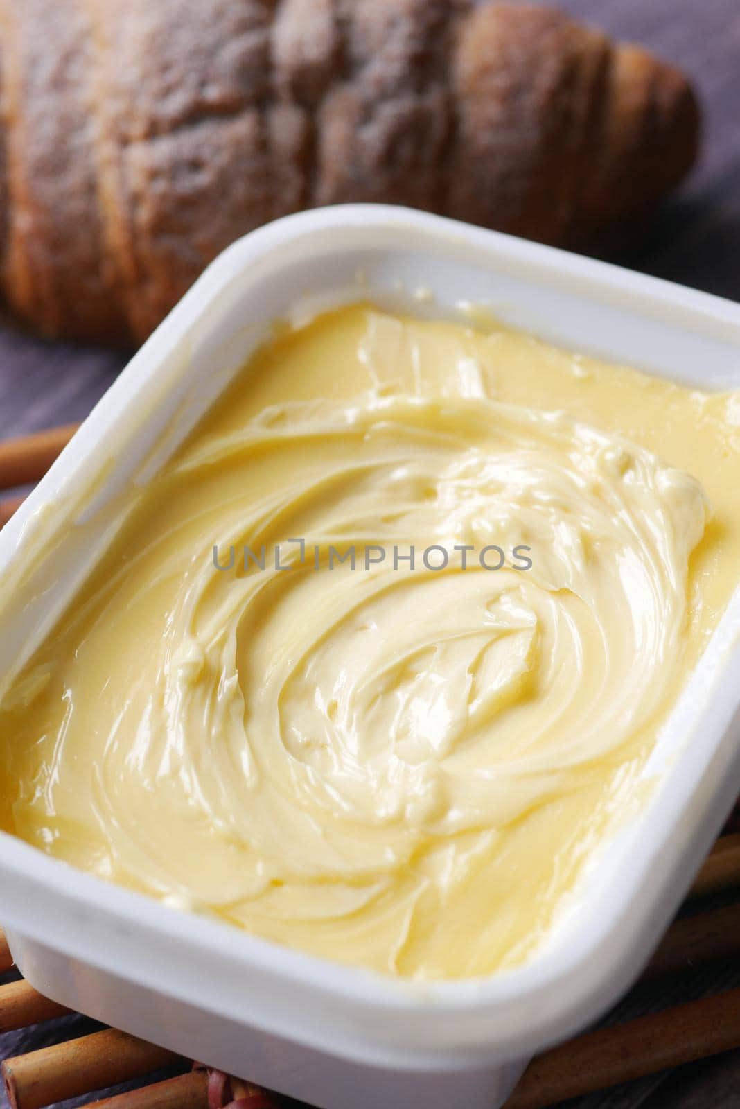 fresh butter in a container with bread on white background .
