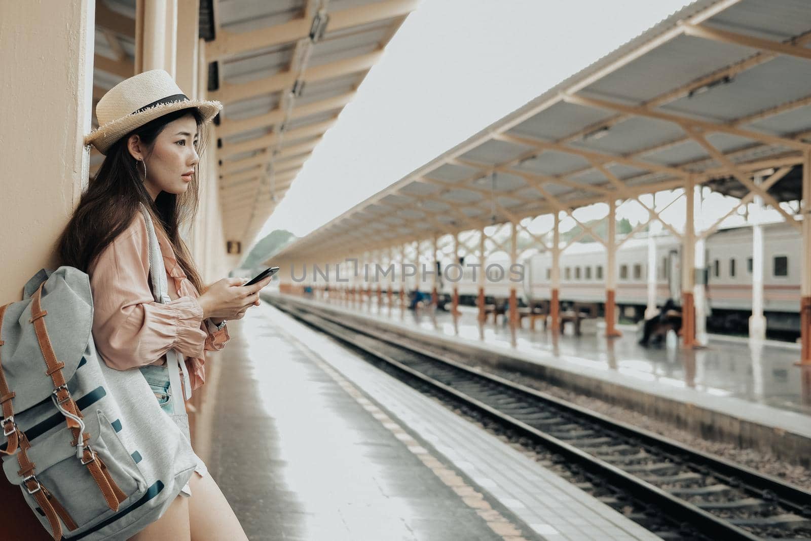 woman traveler with backpack use app on mobile smart phone at train station. trip journey travel concept