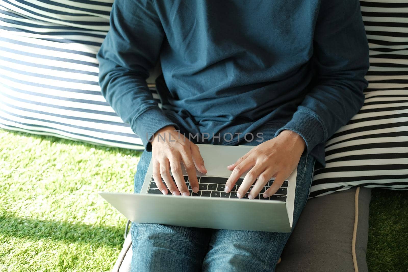 man sitting on floor in living room using computer at home. male teenager student studying doing assignment