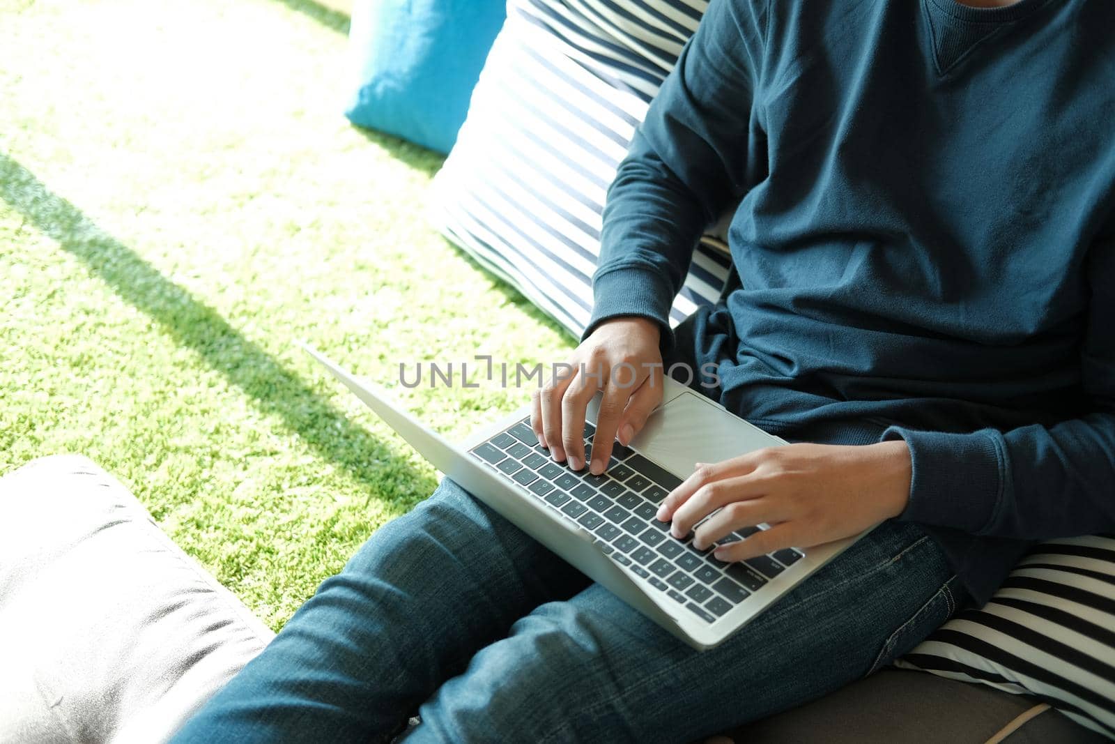 man sitting on floor in living room using computer at home. male teenager student studying doing assignment