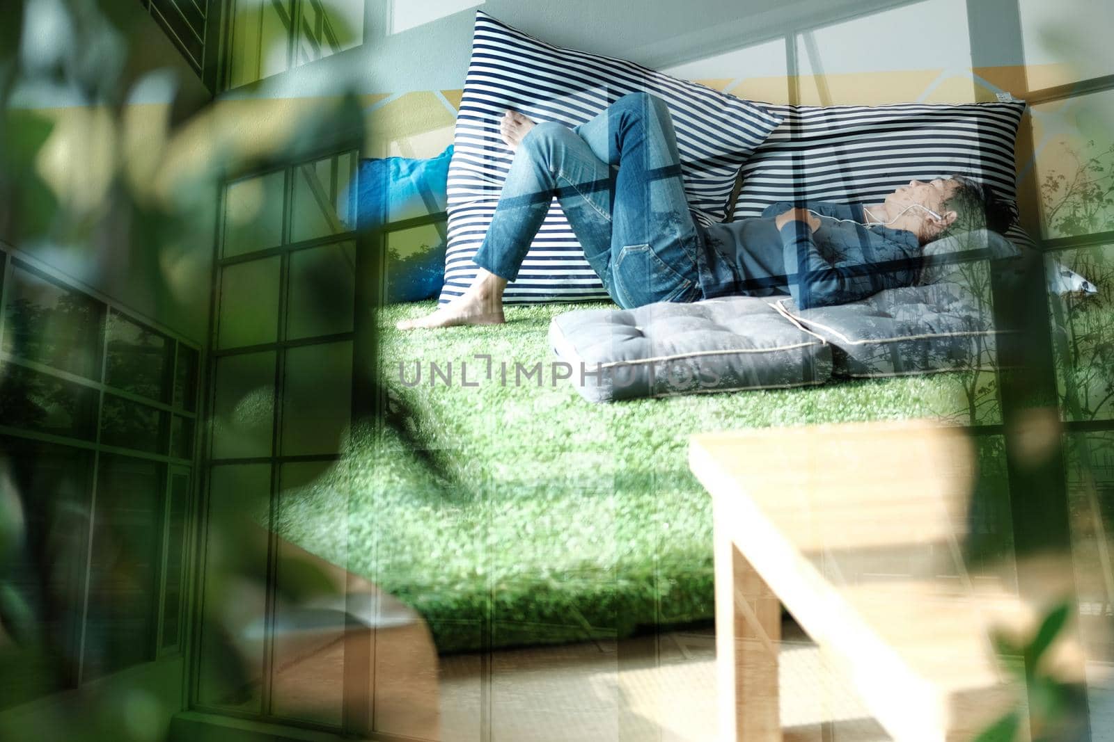 asian male teenager man listening to music from smart mobile phone while lying on floor at home