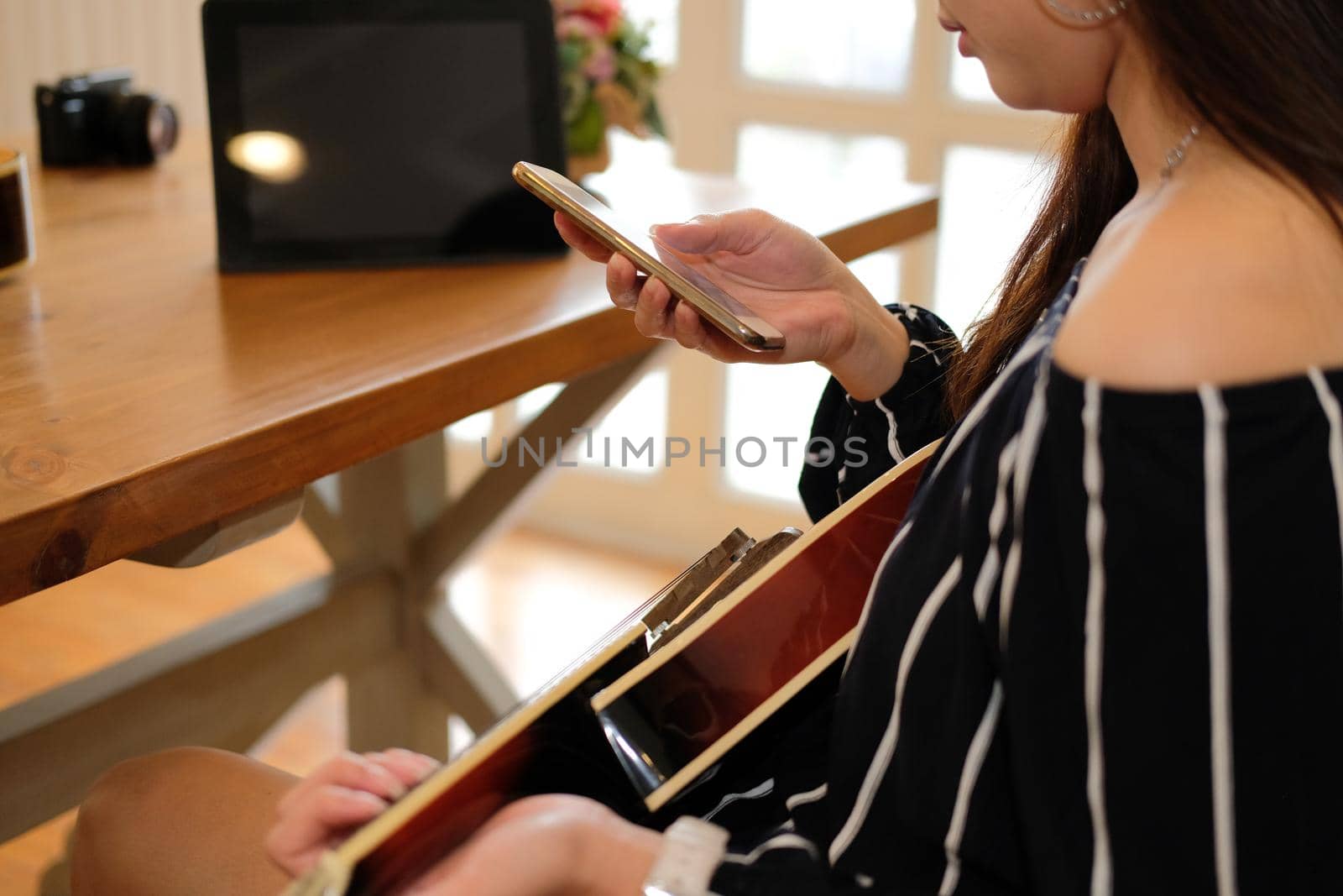 woman playing guitar using mobile smart phone at home