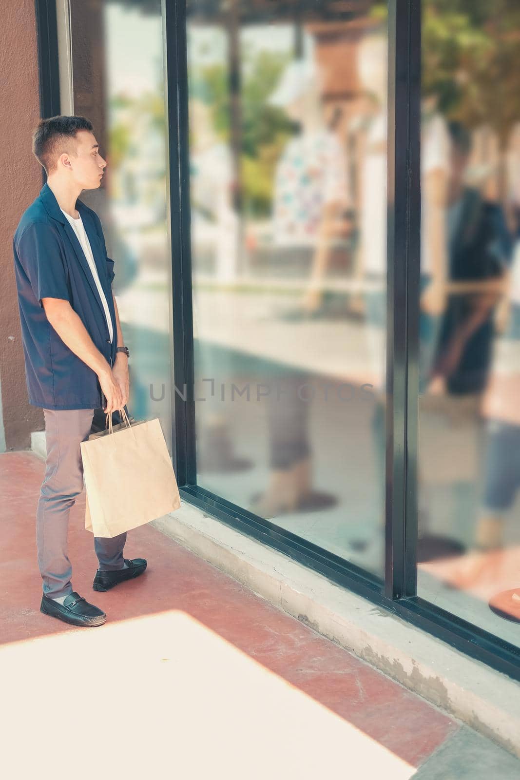 man holding shopping bags looking at shop window by pp99
