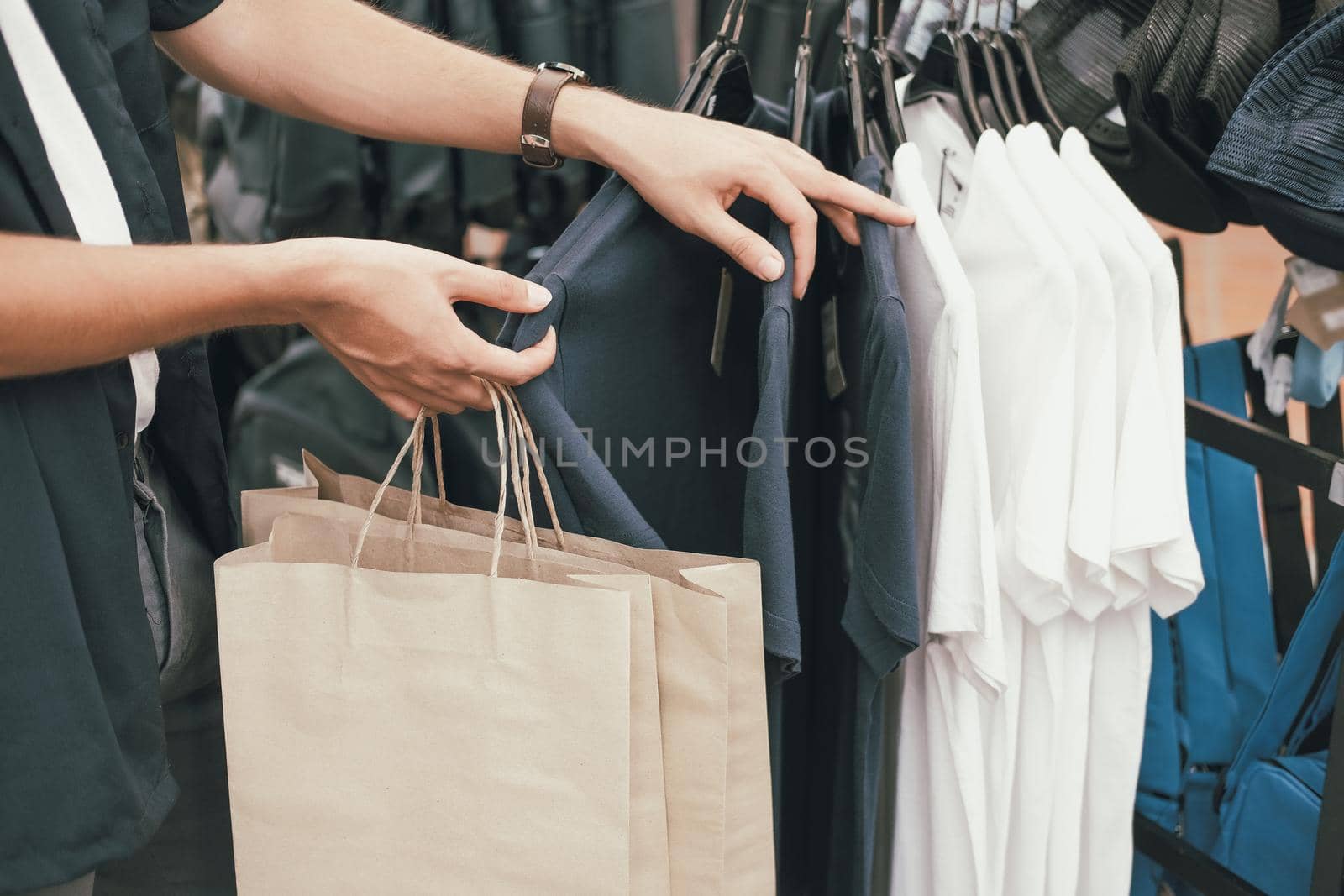 man holding shopping bags choosing clothes at store shop mall