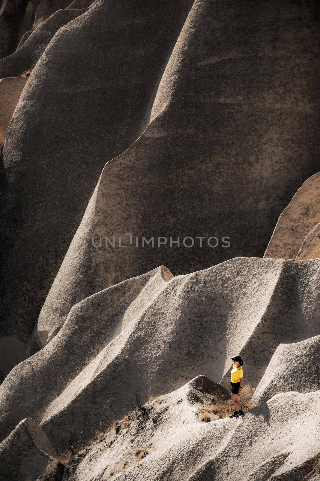 Small figure of tourist standing on stony mountain in Cappadocia, Turkey