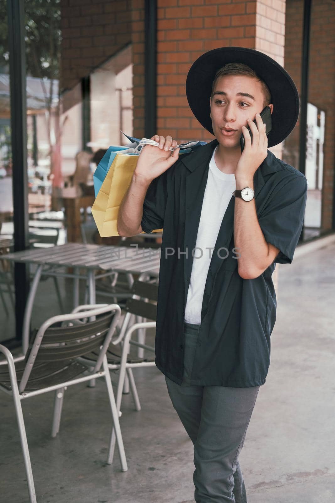 man holding shopping bags & talking on mobile smart phone.  by pp99