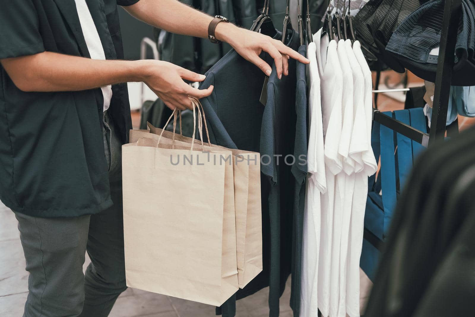 man holding shopping bags choosing clothes at store shop mall