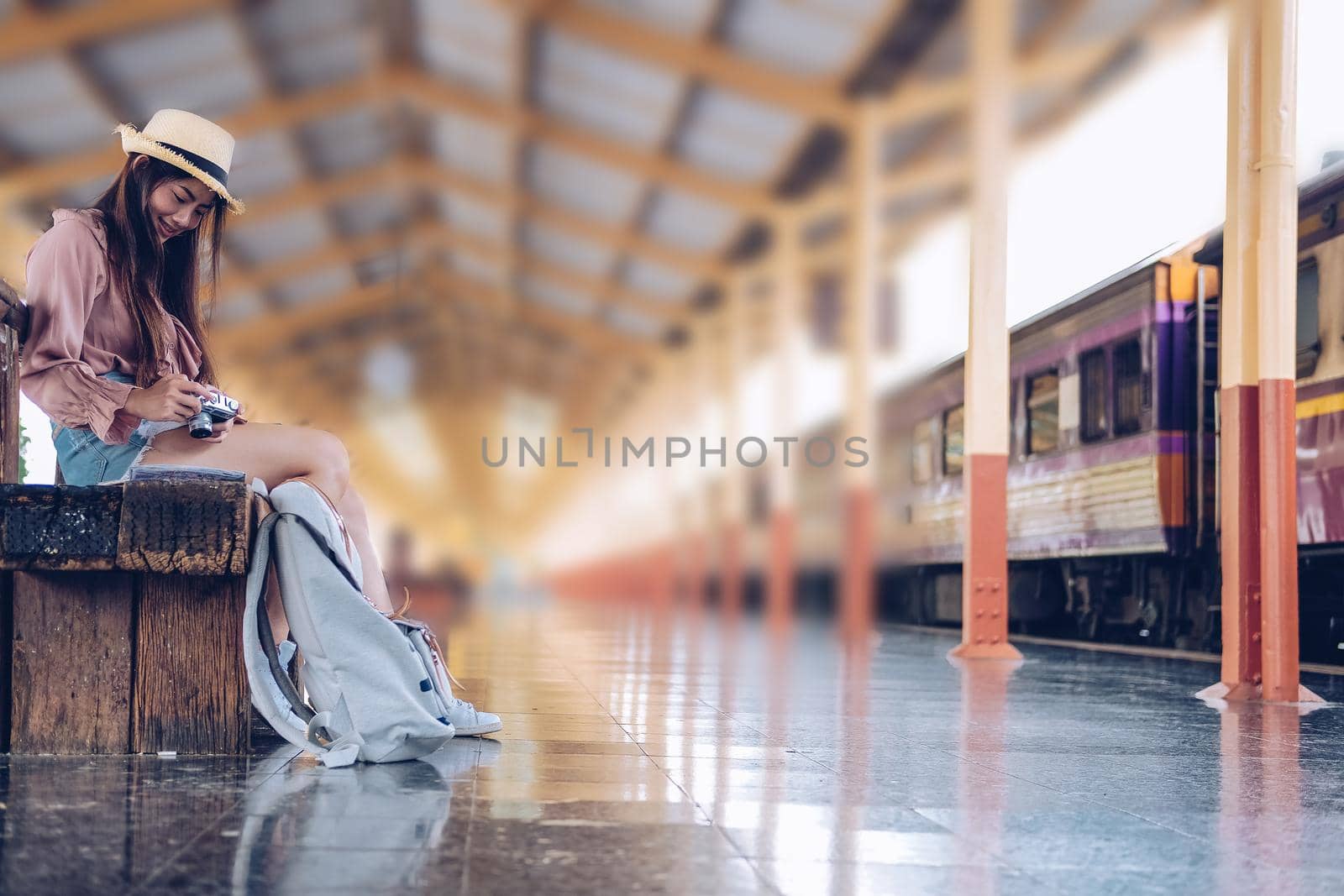 woman traveler holding camera taking photo at train station. travel trip journey concept