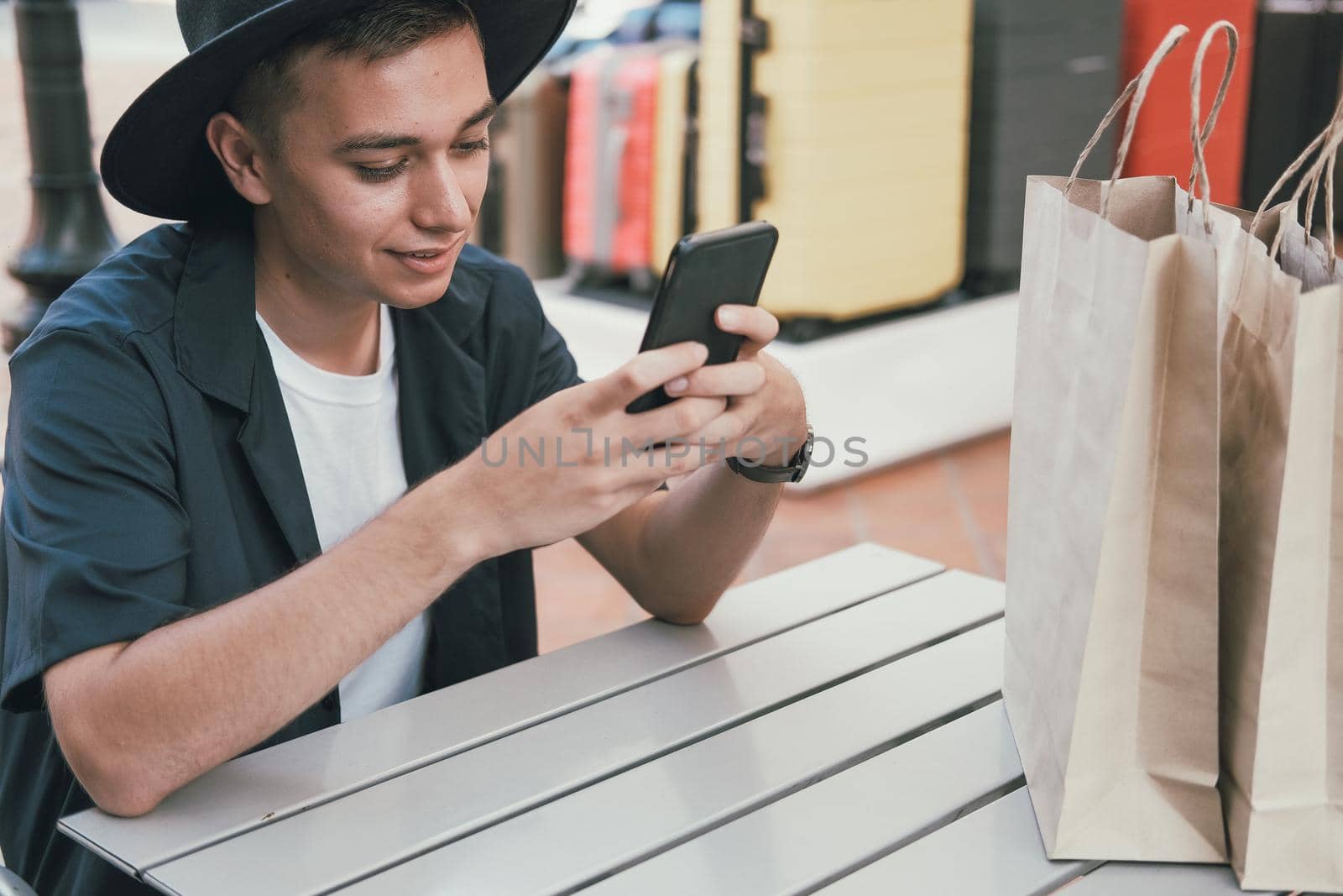 man using mobile smart phone with paper shopping bags. consumerism lifestyle