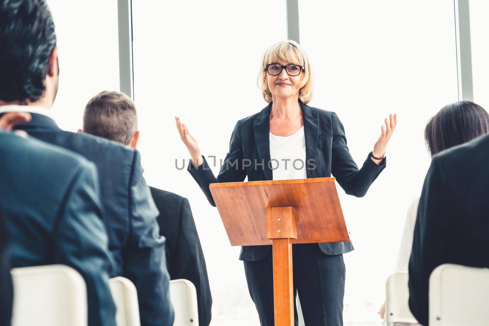 Group of business people meeting in a seminar conference . Audience listening to instructor in employee education training session . Office worker community summit forum with expert speaker .