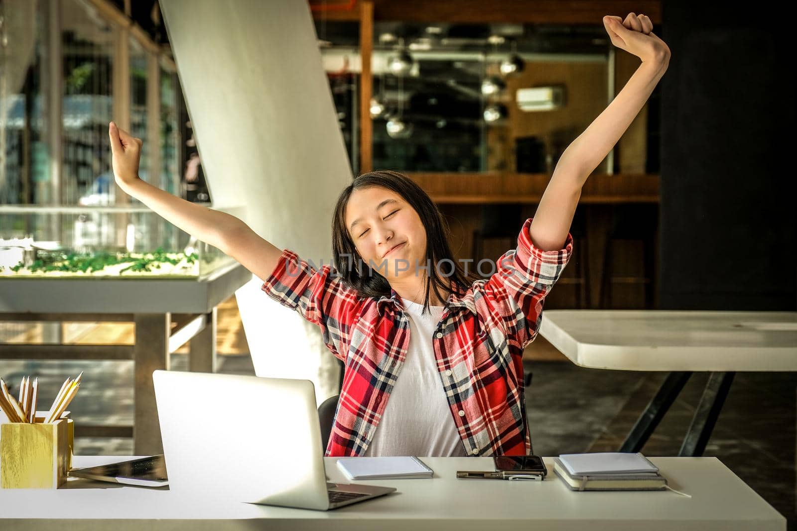 relaxed asian woman girl teenager stretching arms above head relaxing resting at co-working space