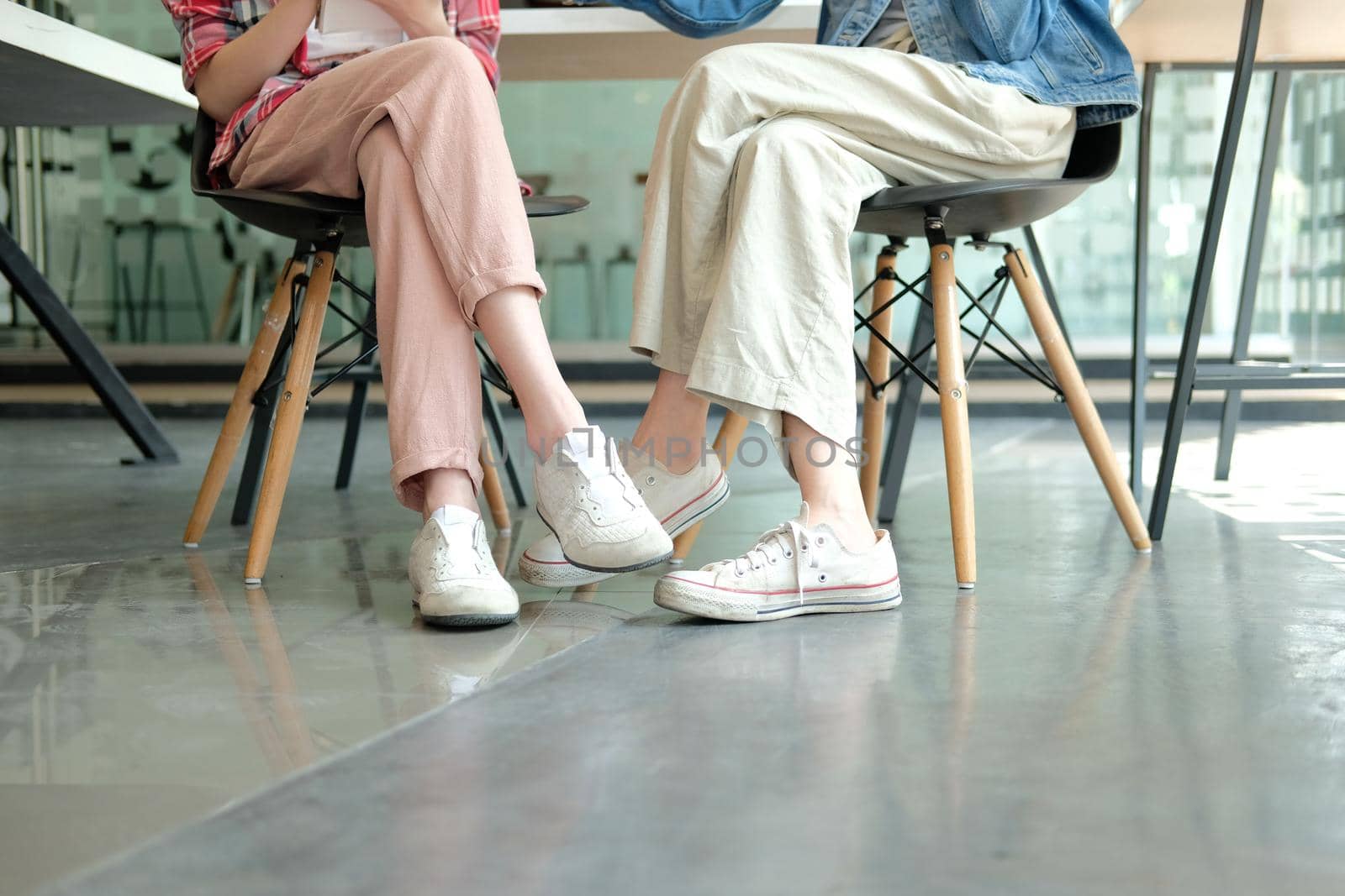 girl teenager friends legs wearing white sneakers sitting talking together. friendship leisure lifestyle