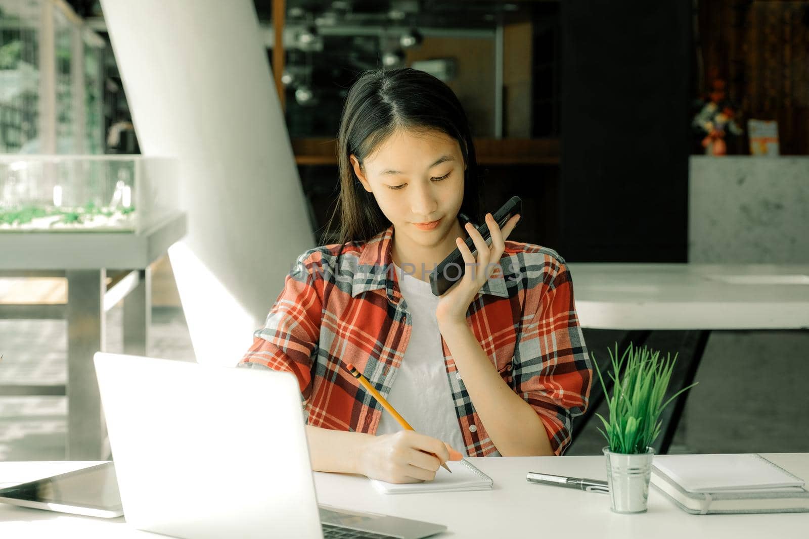 woman girl teenager freelancer talking on phone writing note at workplace