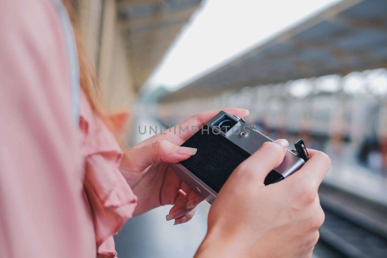 woman traveler holding camera taking photo at train station. travel trip journey concept