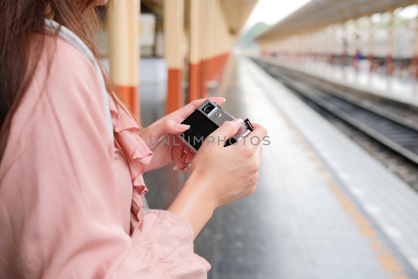 woman traveler holding camera taking photo at train station. travel trip journey concept