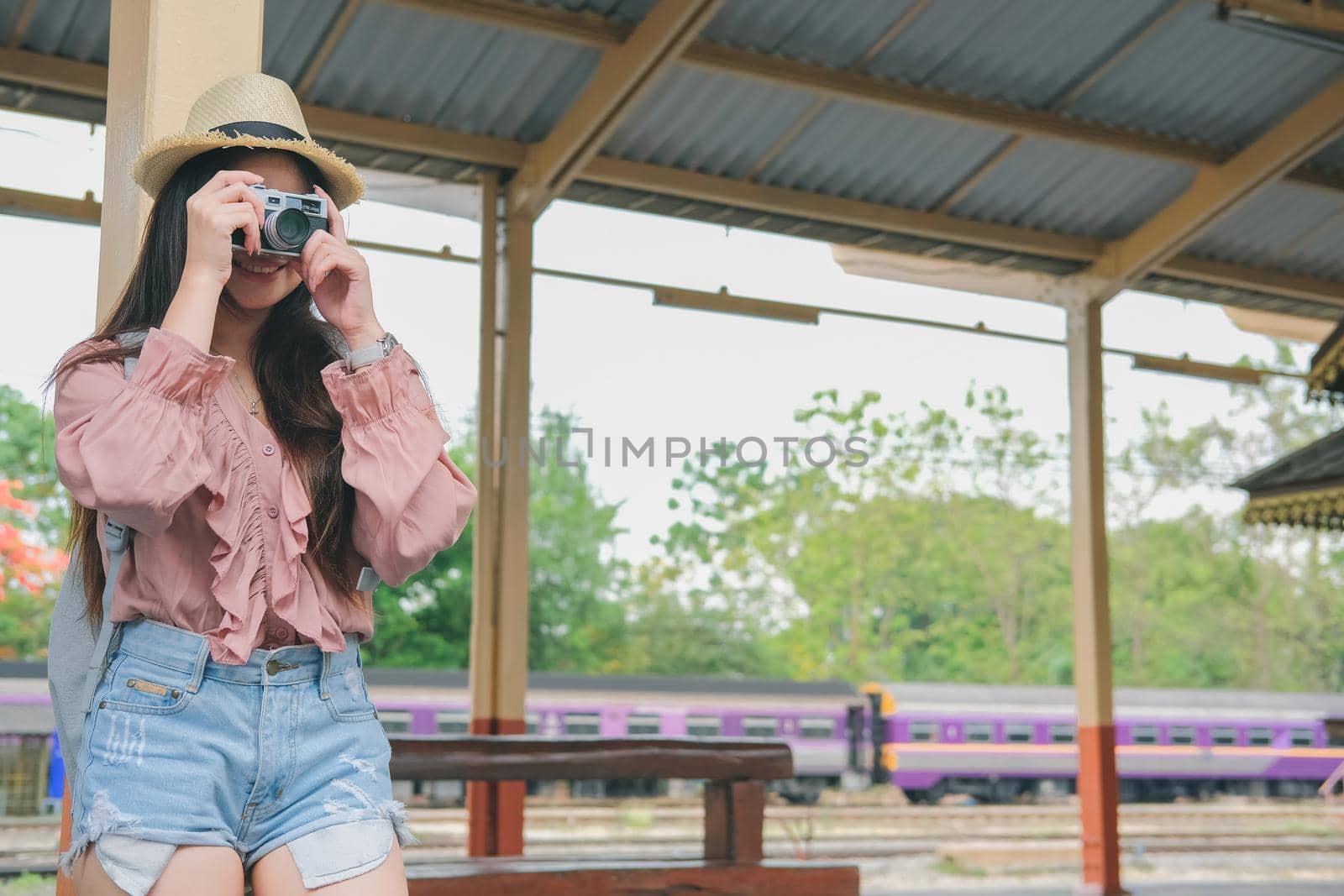 woman traveler holding camera taking photo at train station. travel trip journey concept