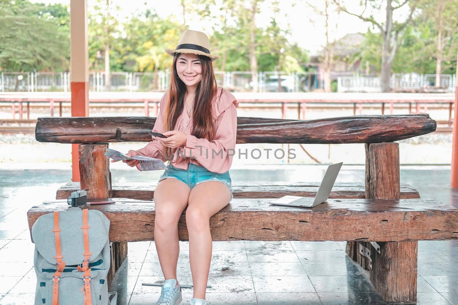 young woman traveler with mobile smart phone & map at train station. Travel journey trip concept