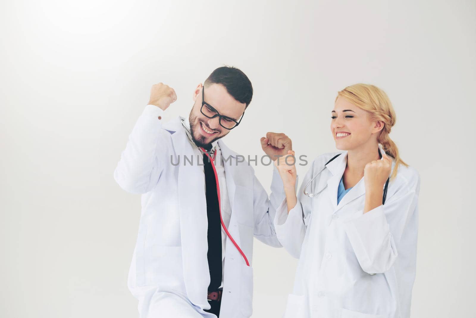 Happy successful doctor celebrates victory in hospital office with another doctor standing beside her for the success of patient treatment.