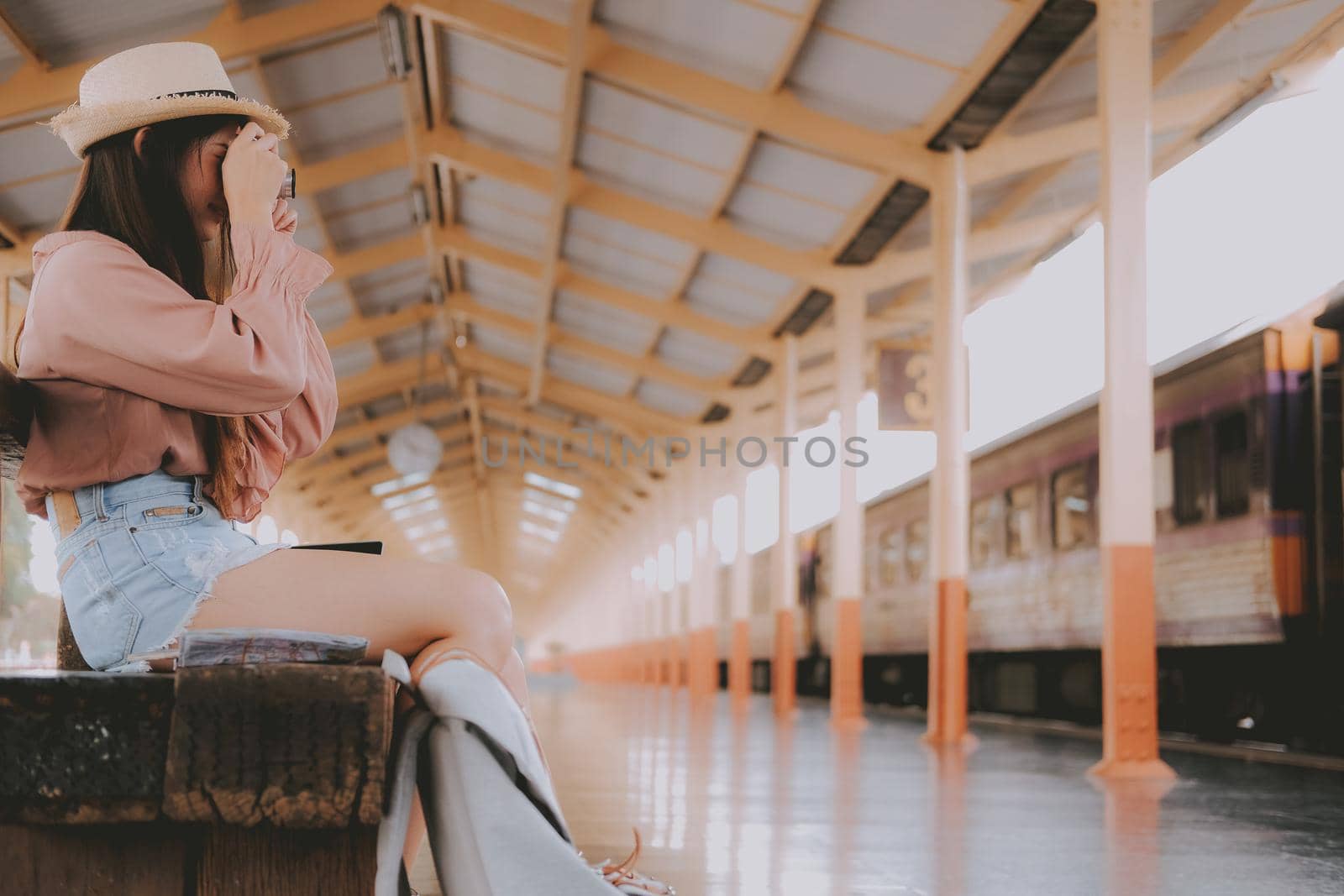 woman traveler holding camera taking photo at train station. travel trip journey concept