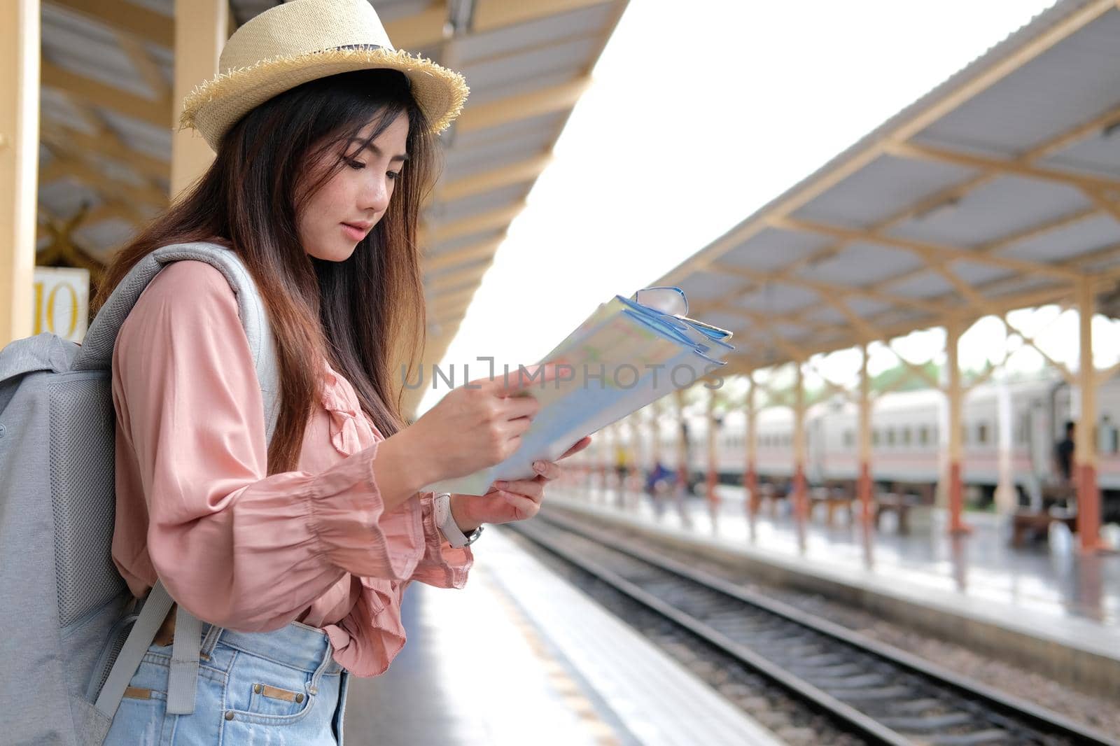 woman backpacker traveler looking at map with backpack at train station while waiting for train. journey trip travel concept by pp99