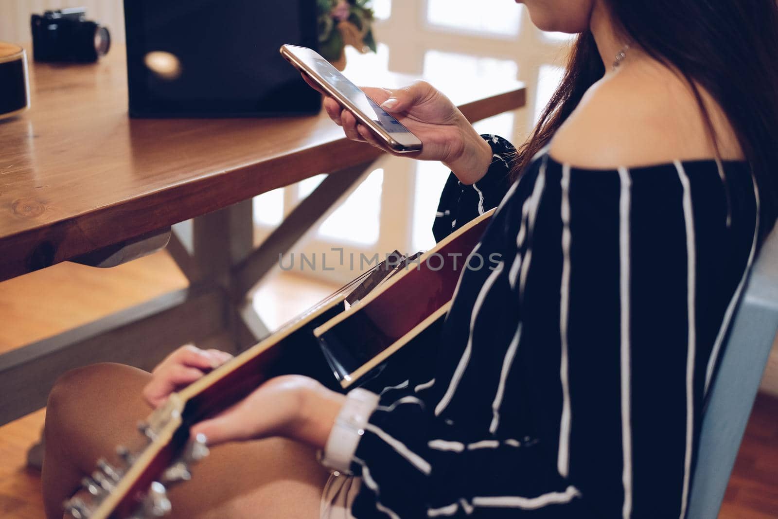 woman playing guitar using mobile smart phone at home