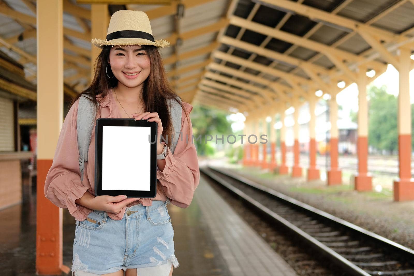 woman traveler showing tablet with blank screen at train station. Travel journey trip concept by pp99