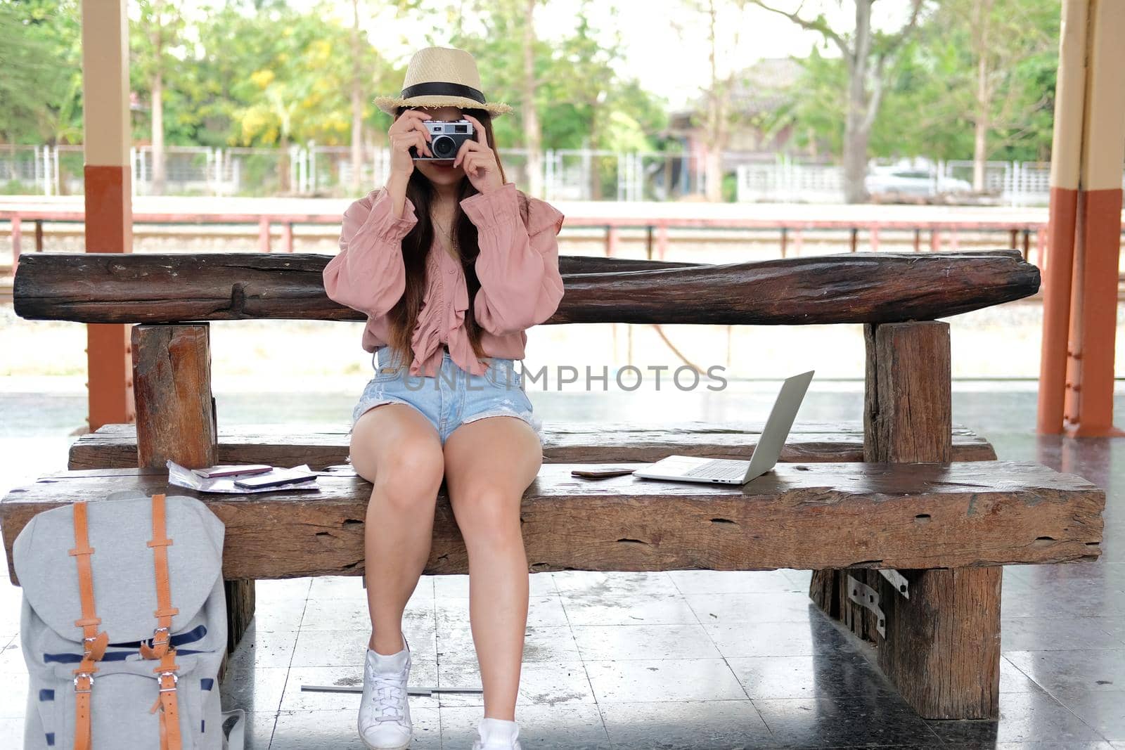 woman traveler holding camera taking photo at train station. travel trip journey concept