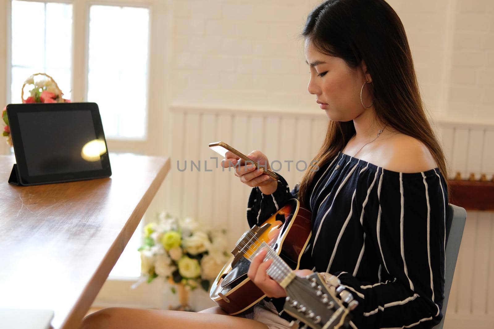 woman playing guitar using mobile smart phone at home
