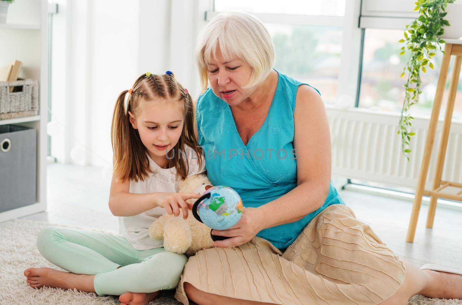 Grandmother and granddaughter examining globe by GekaSkr